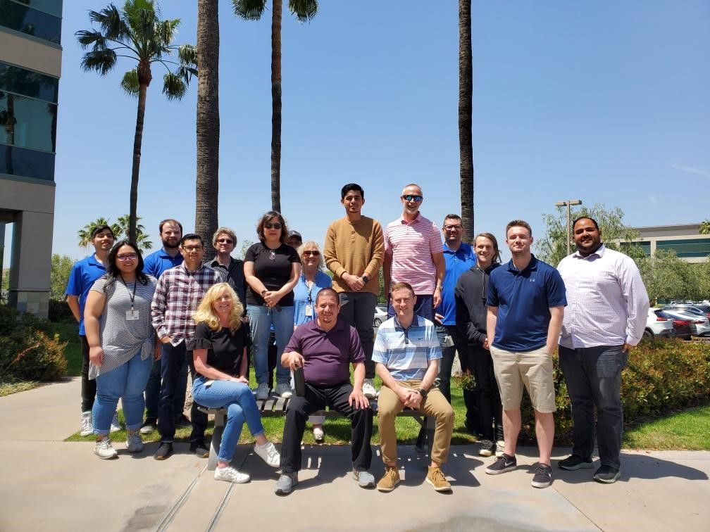 Group of PGIA employees posing for a group photo with a sunny blue sky