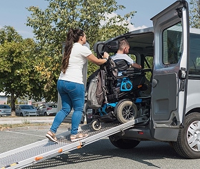Person pushing wheelchair into van