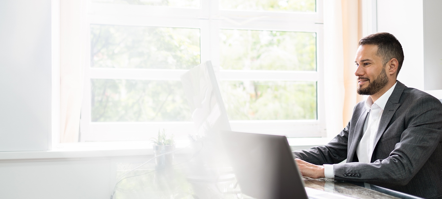 A man in a suit working on a computer.