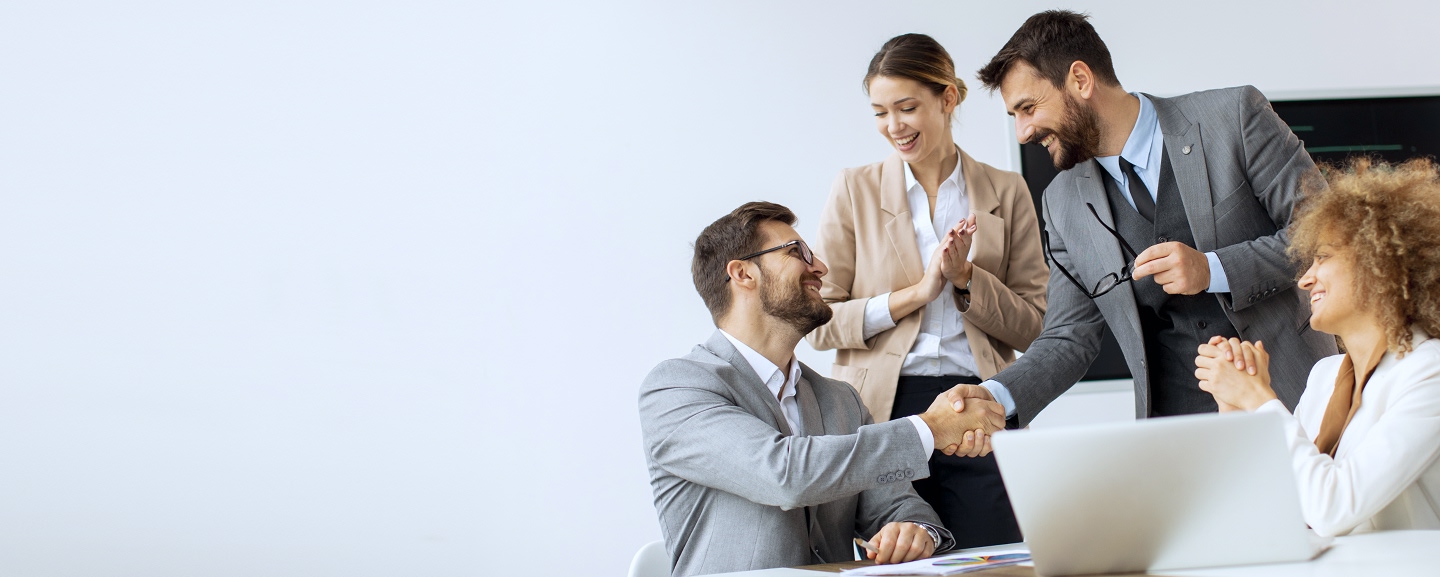 Four happy business people in front of a laptop
