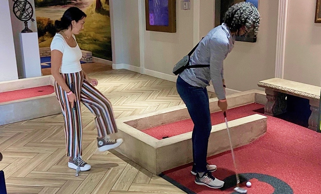 Two employees playing mini golf.
