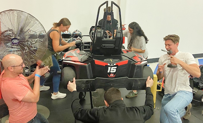 Five employees building a go cart.